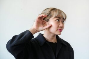 Une femme adulte réfléchie aux cheveux blonds posant à l'intérieur, la main sur l'oreille.