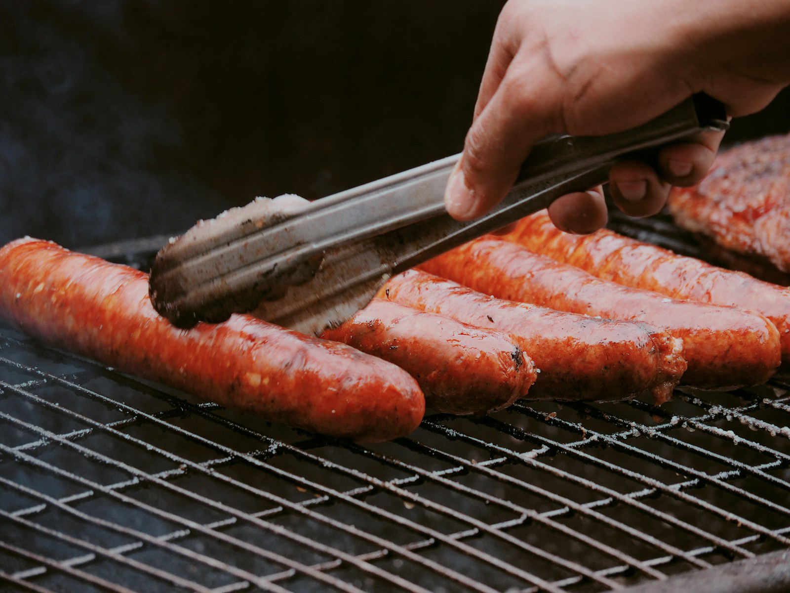 Des saucisses sont en train de griller sur un barbecue.
