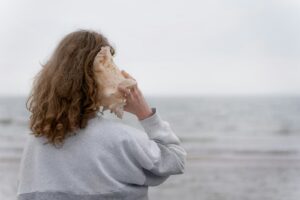 une femme tenant un coquillage devant son visage